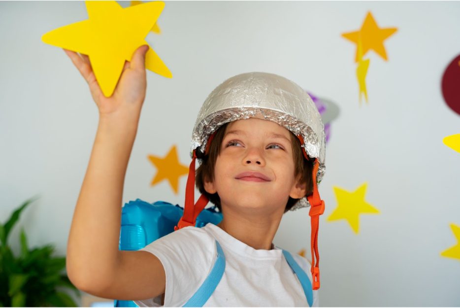 Момче, облечено като астронавт, посяга към хартиена звезда